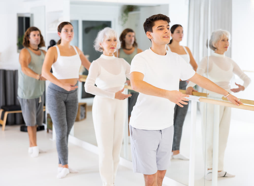 Concentrated women and men rehearsing ballet dance in dance studio