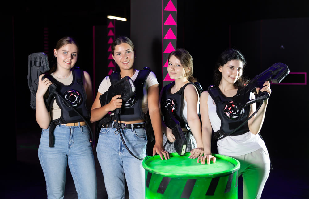 Group portrait of girlfriends with guns in their hands in laser tag room