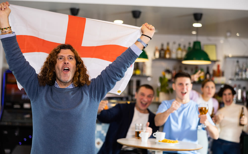 Glad males and females with England flag clinking glasses with beer on party