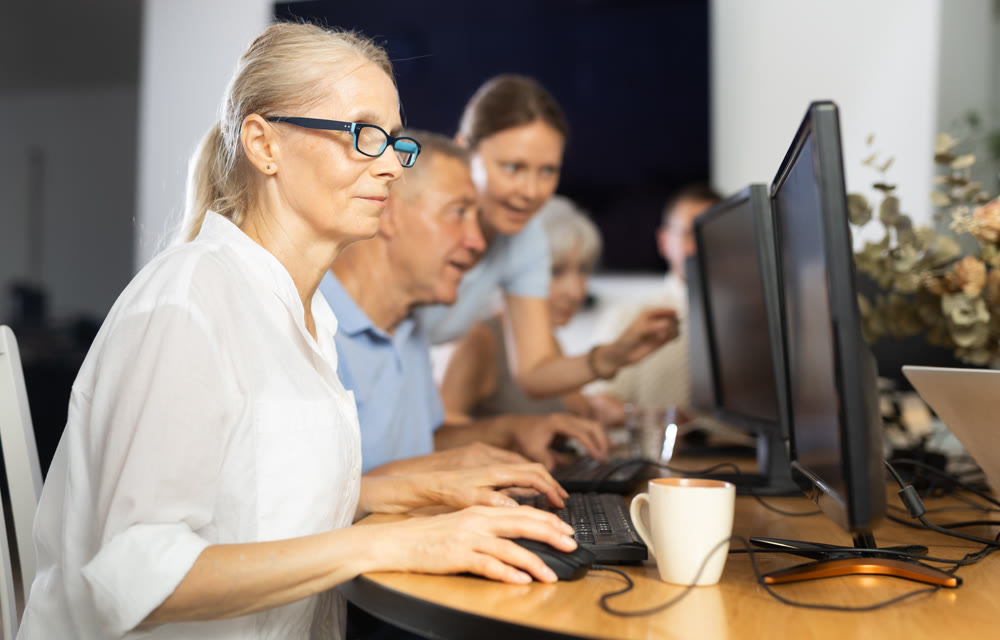 Focused senior woman in glasses attending group computer class