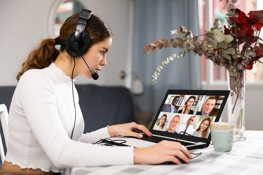 Young woman talking with colleagues during video conference at home