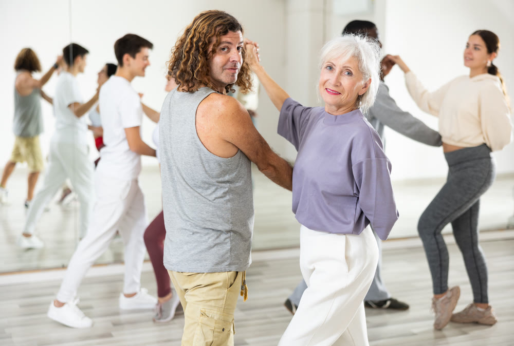 Smiling mature woman and man learning pair dances