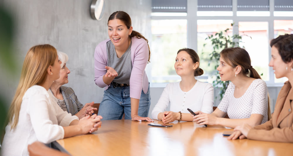 Group of people of different ages sitting around table and communicating