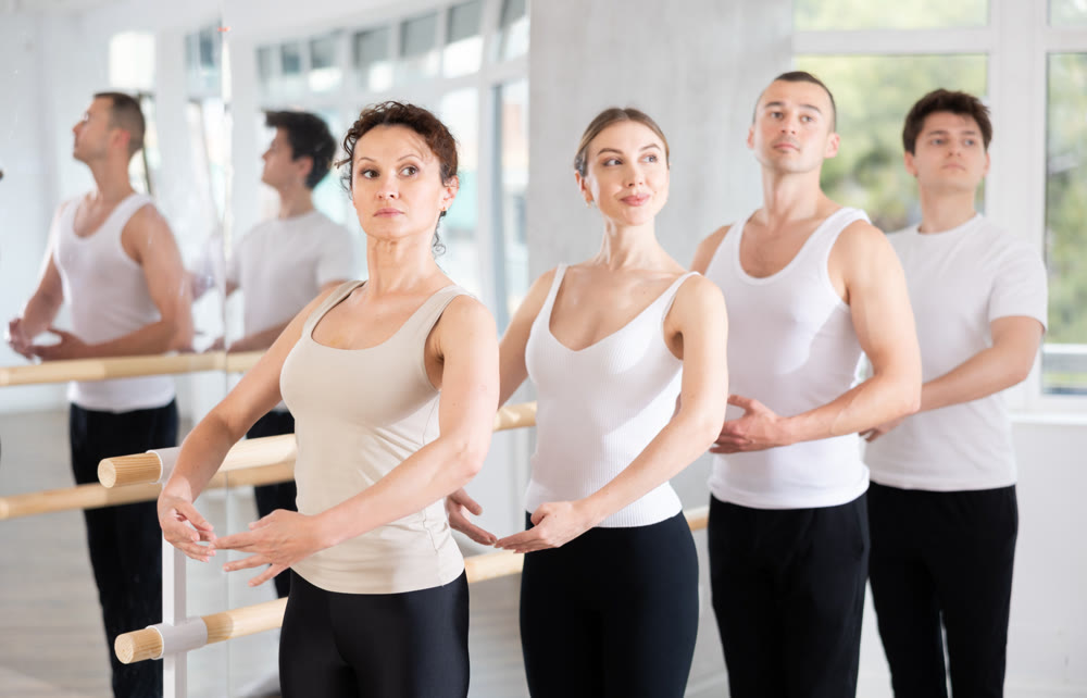 Amateur ballerina mastering first position at barre in ballet studio