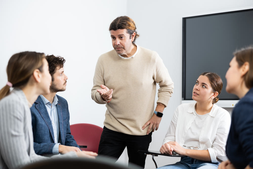 Competent male tutor teaching students in college classroom