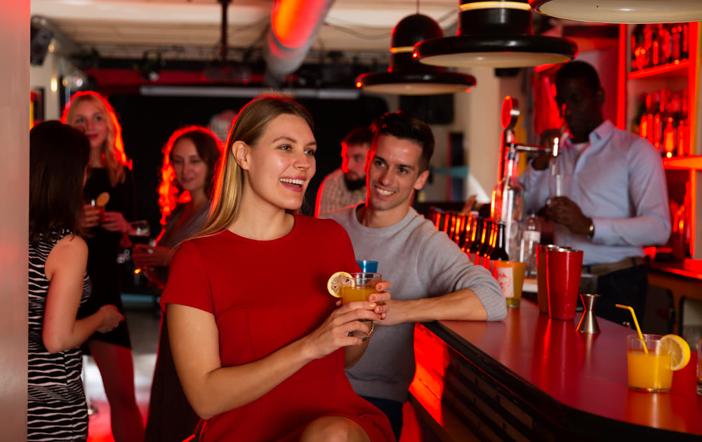 Portrait of happy young woman with colleagues enjoying corporate party in the bar