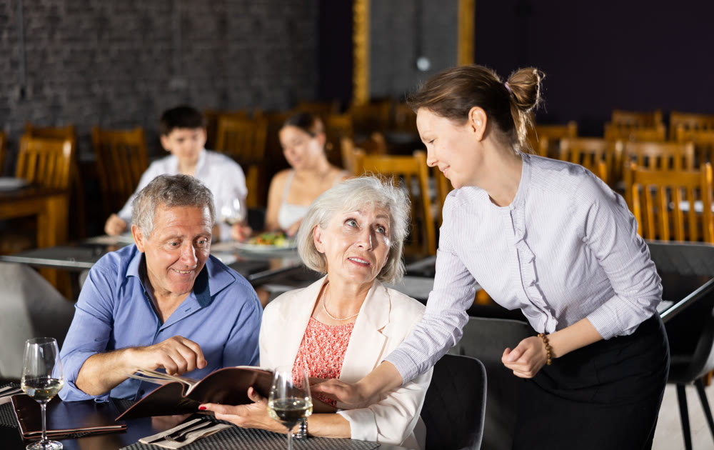 Woman waiter taking order from elderly couple in restaurant