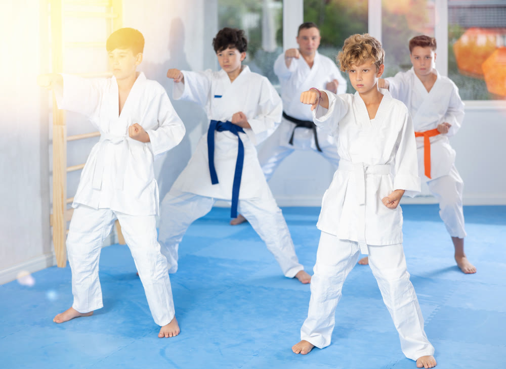 Teenage boy with group of karate practitioners performing kata routines