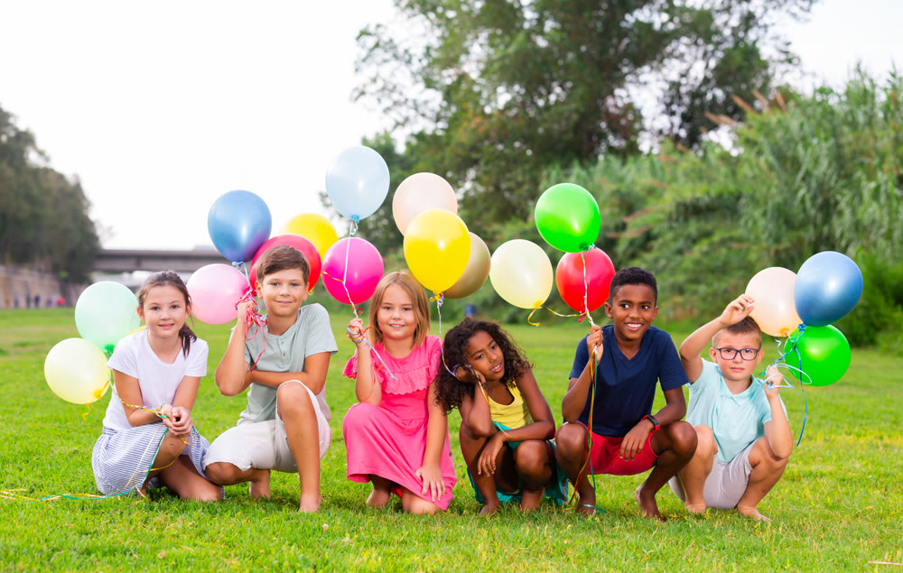 Barefoot kids playing with balloons on grass
