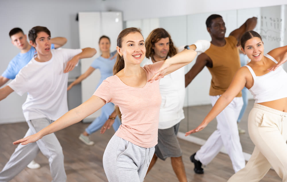Group of active women and men practicing energetic dance in modern dance studio