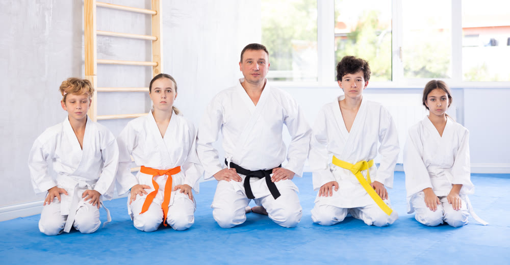 Group of children and karateka trainer sitting on floor