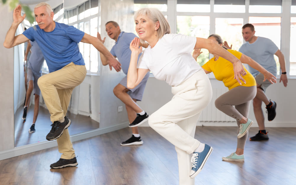 Cheerful elderly woman learning dynamic dances at group choreography lesson