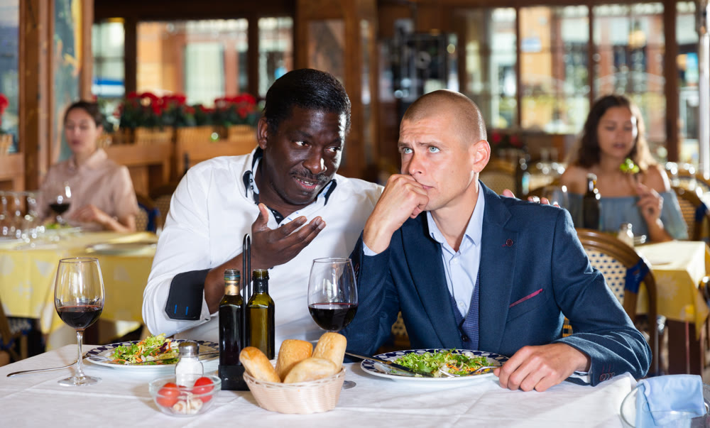 Man talking with upset friend at restaurant