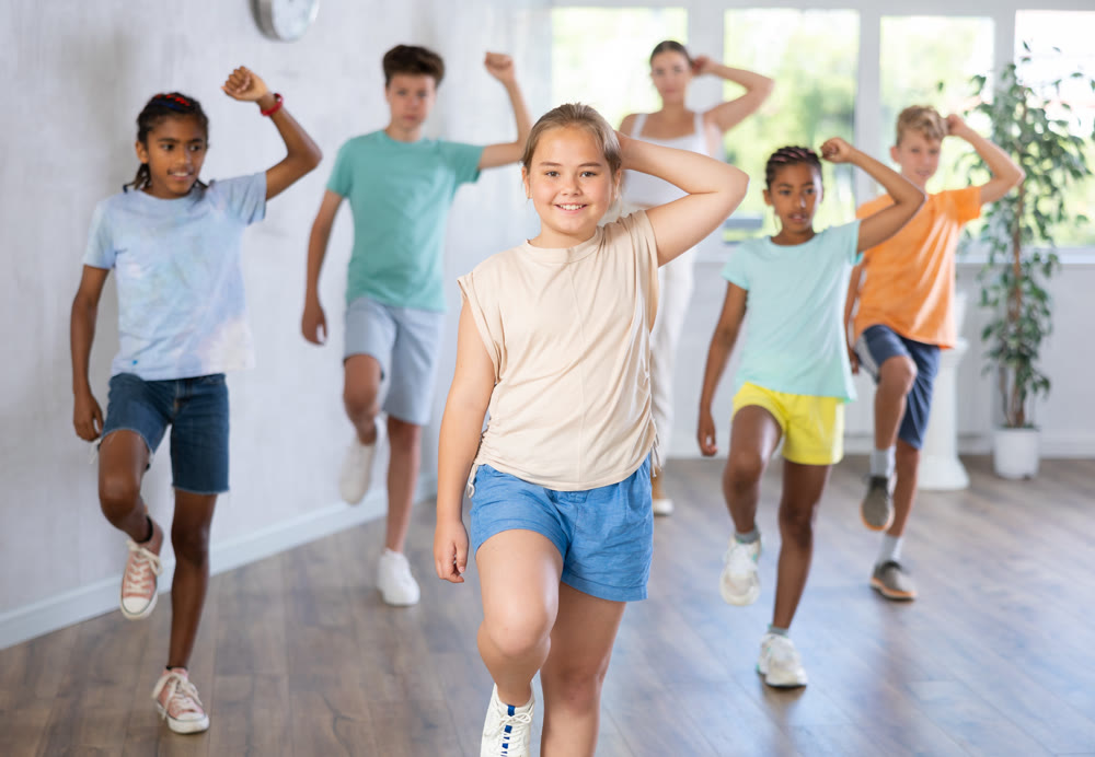 Girl child perform social dance vogue with friends and female teacher in background