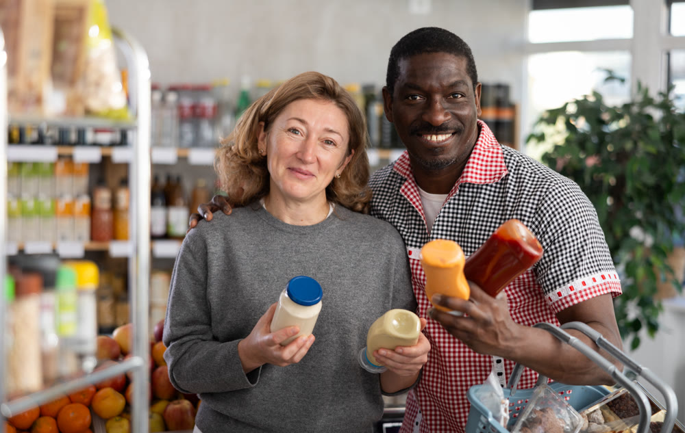 African man with European wife buyer select thoughtfully at bottles of different sauces