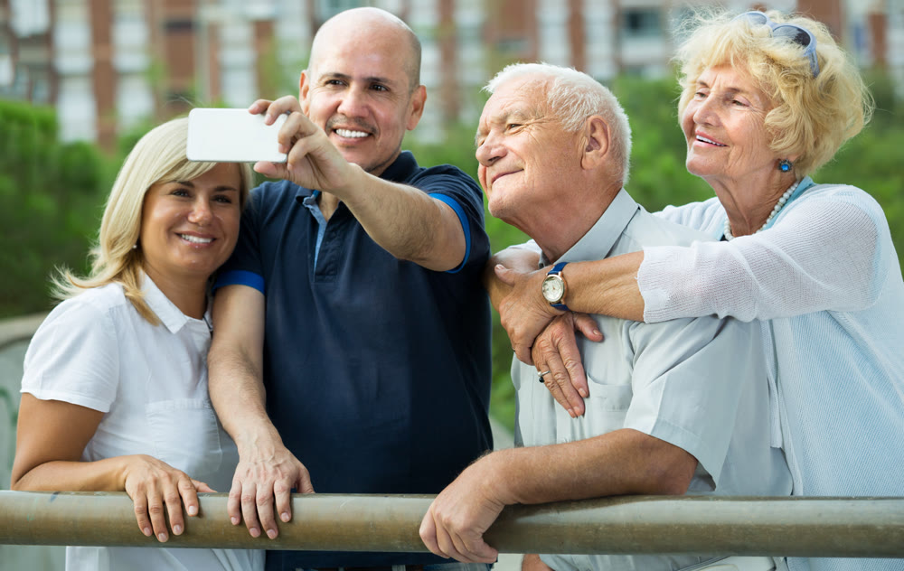 Smiling mature people taking selfie in park together