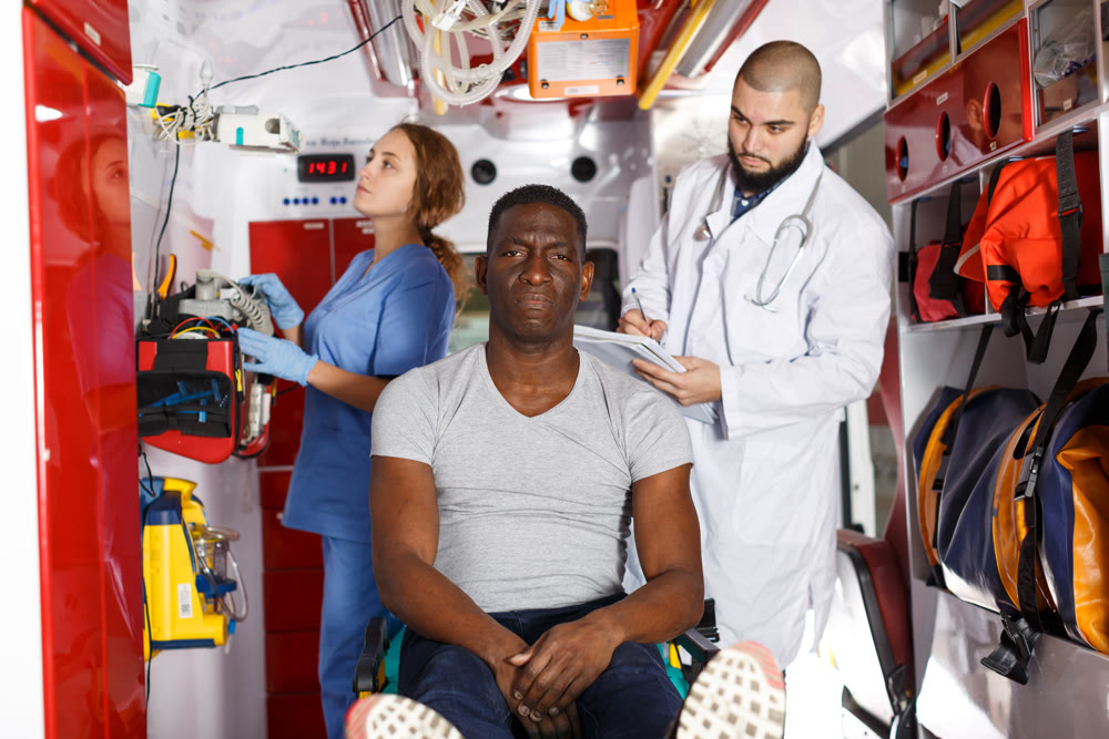Smiling afro man sitting on stretcher