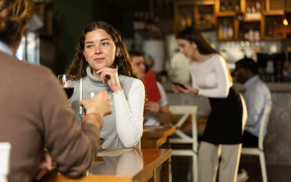 Girl in cafe sits opposite male companion, has nice conversation