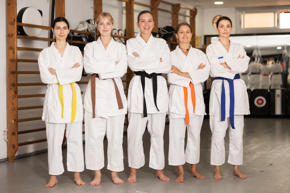 Team of young female martial arts athletes is standing in gym