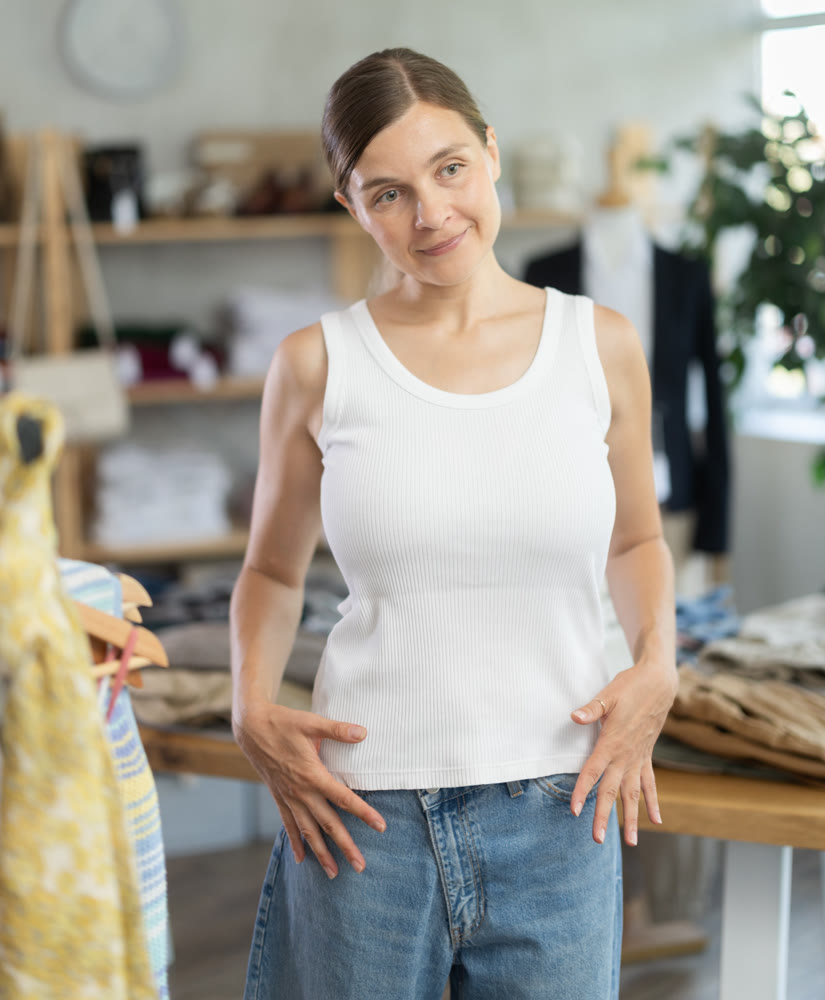 Adult woman trying on white tank top in store