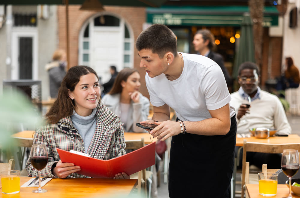 Male waiter taking order from a woman in a restaurant
