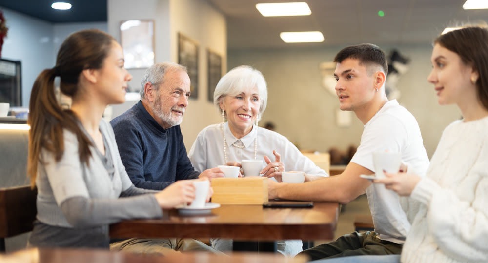 In restaurant, young family and mature parents enjoy festive lunch, celebrating important event