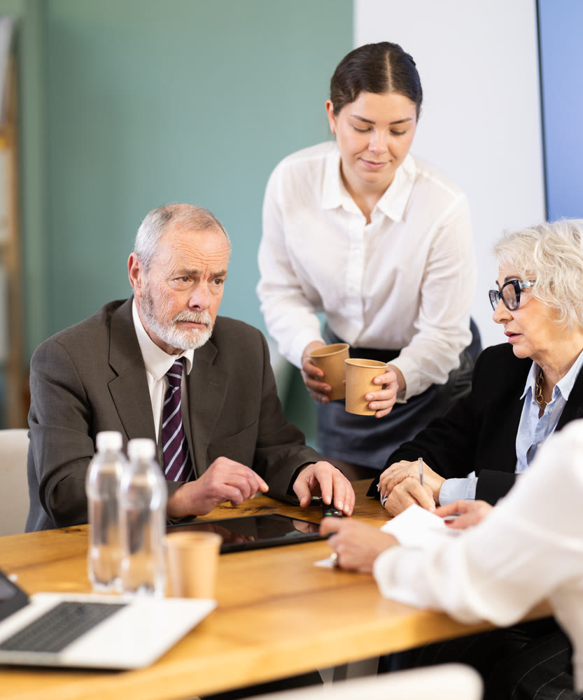Elderly man leading meeting with senior colleagues at table