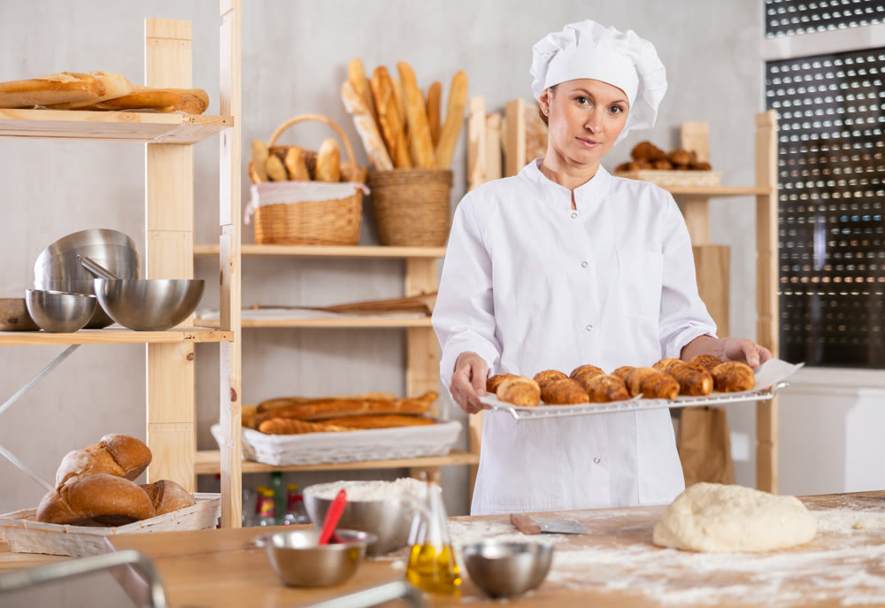 Adult woman with fresh croissants in bakery