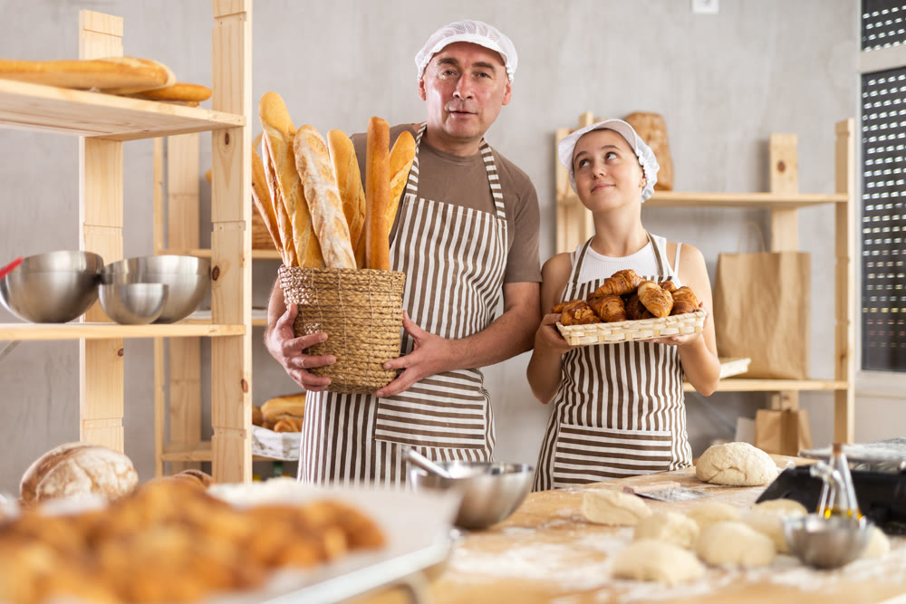 Teenage girl and male baker holding bakery products