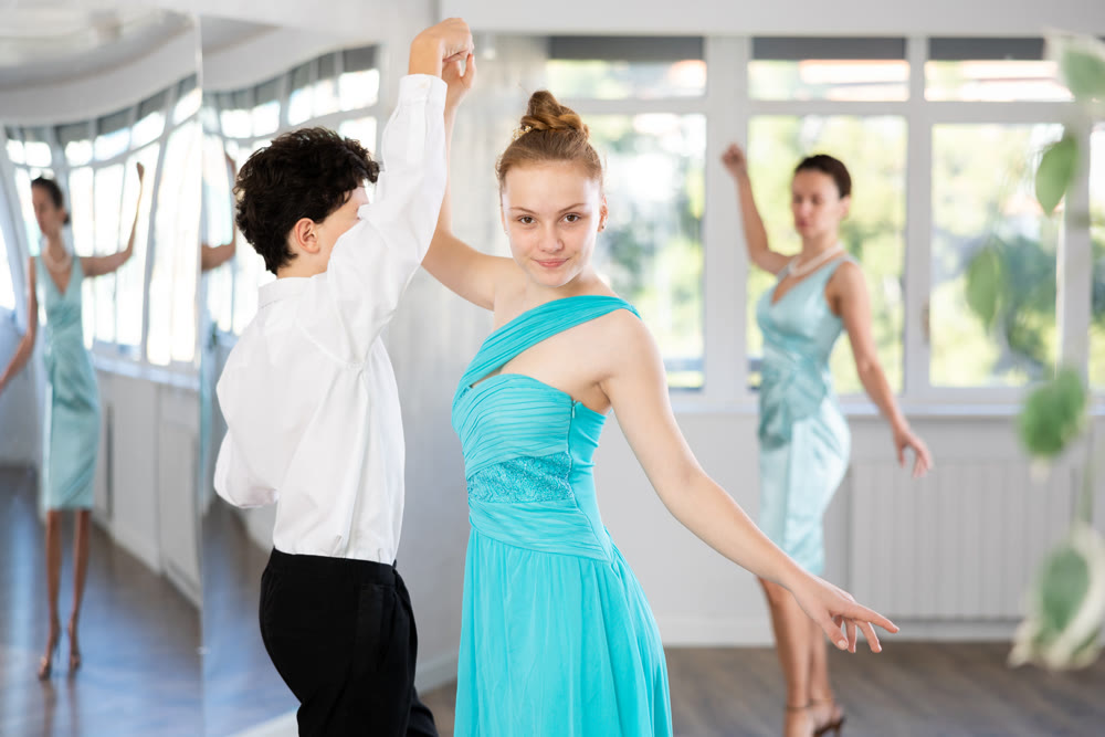 Couple of teenagers in evening dresses are learning to dance an polonaise dance