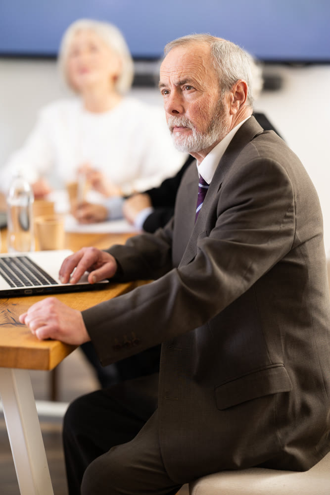 Elderly man in group watches presentation given by young secretary