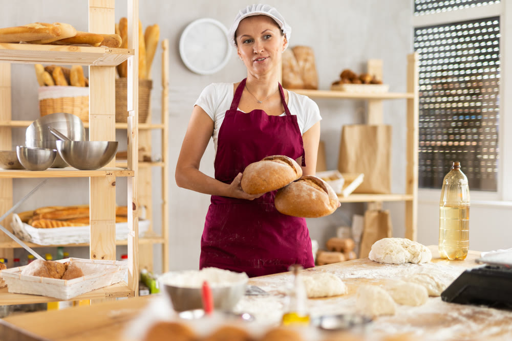 Bakery woman employee holds ready made bread of bread on tray