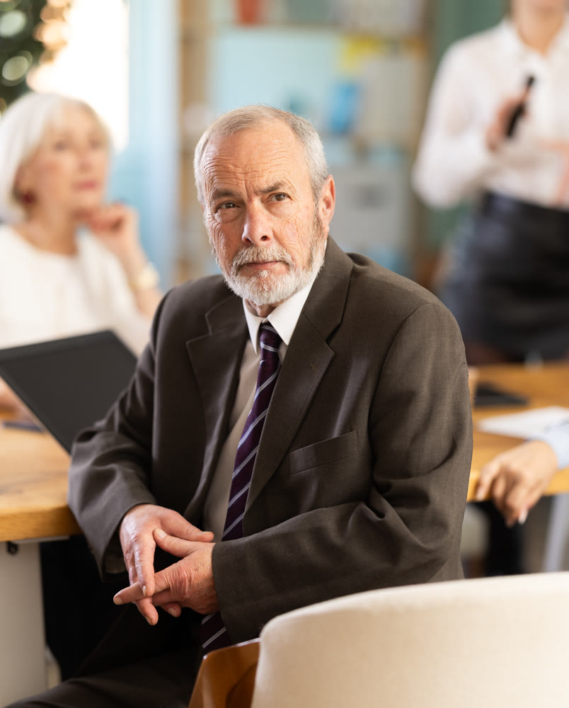 Elderly man in group watches presentation given by young secretary