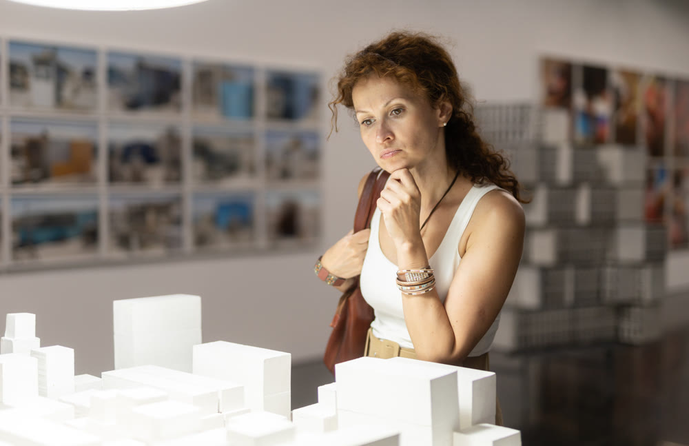 Female visitor observing white sculpture installation in museum