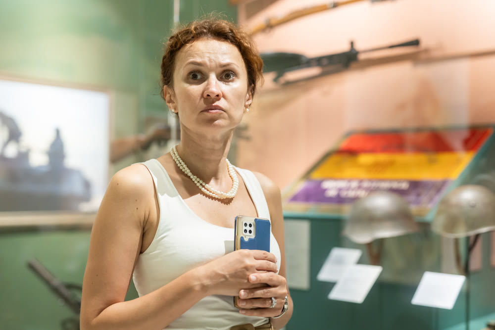 Middle-aged woman looking at shotguns displayed in military museum