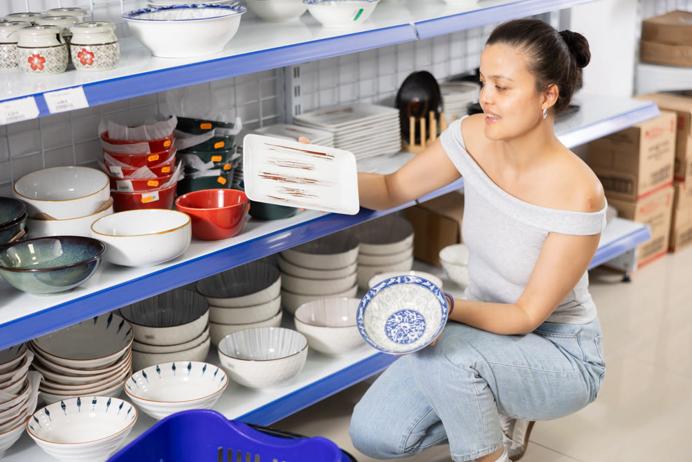 Woman looking for new plates at store of household goods