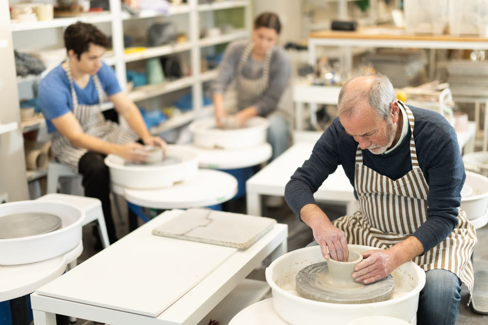 Eldery man shaping pottery on wheel in ceramics studio