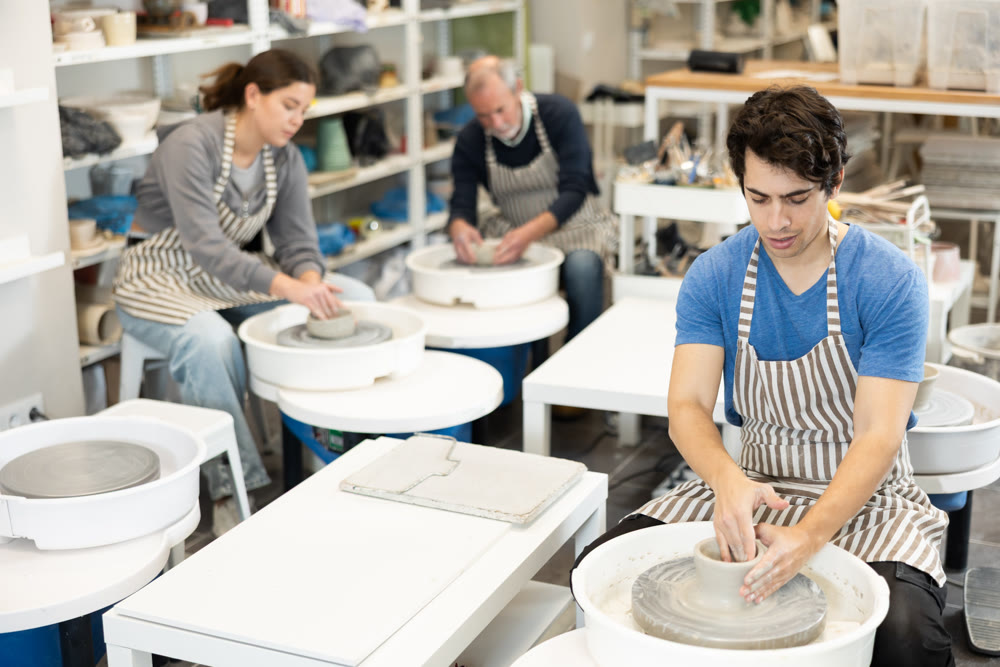 Guy potter works on potter wheel to create clay cup