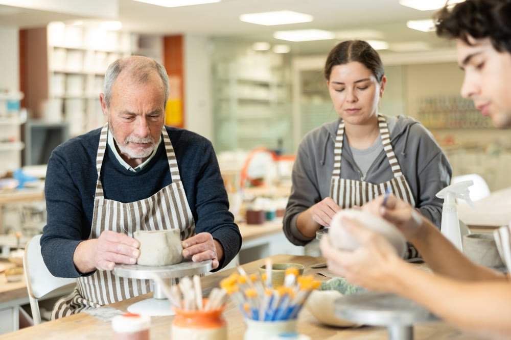 Young woman and man and elderly man crafting ceramics