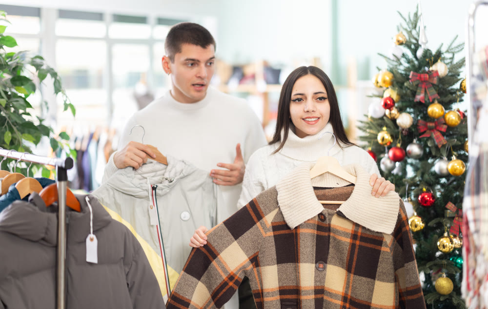 Young couple choosing coat or jacket for girl in clothing store