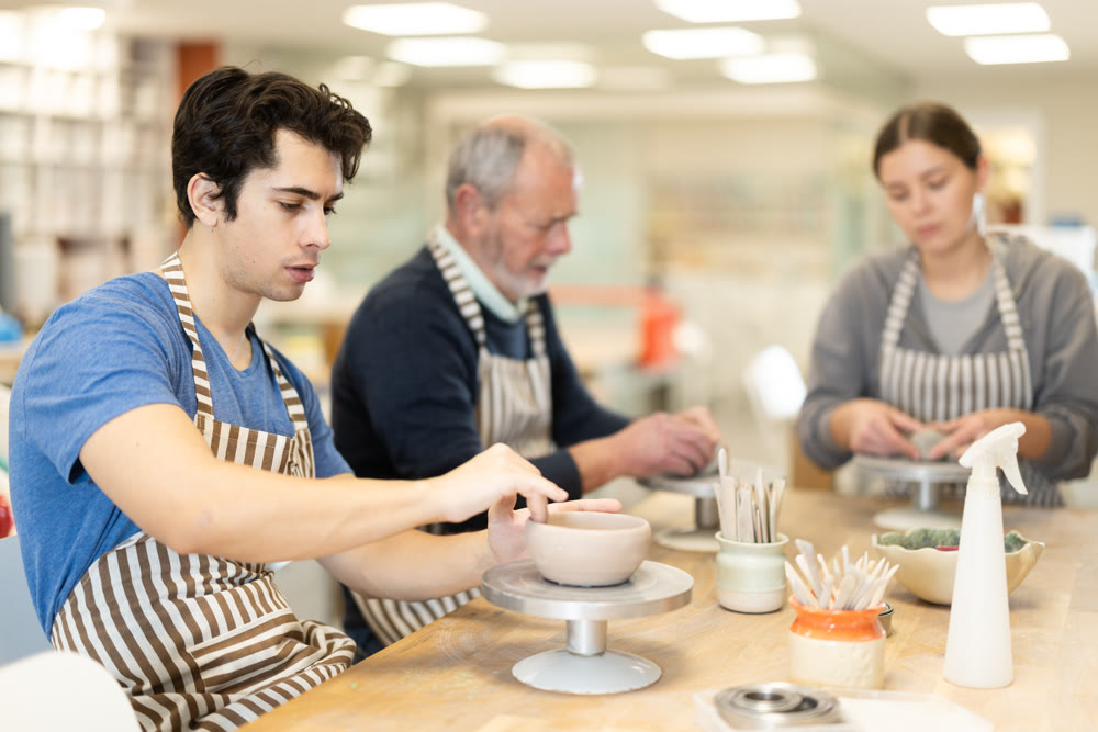 Young man sculpts ceramic piece in workshop