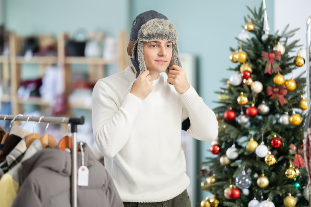 Young man tries on fur hat in store