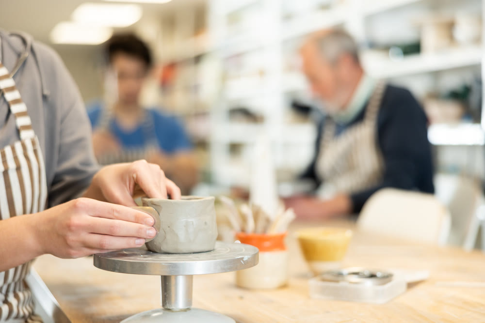 Closeup of female hands sculpting at a table in pottery studio