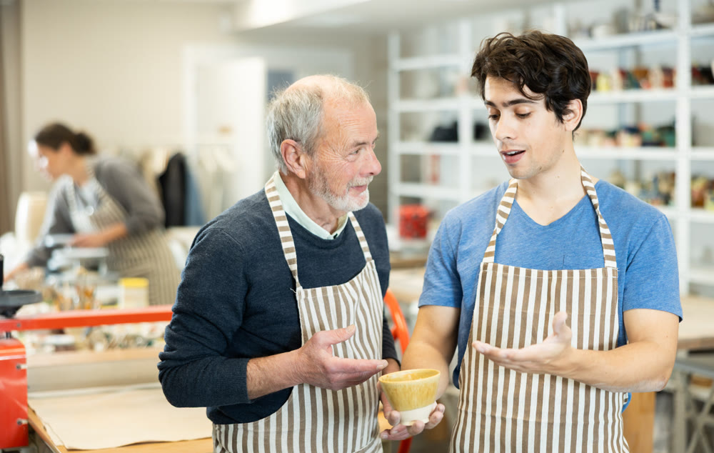 Young man showing ceramic piece to elderly man