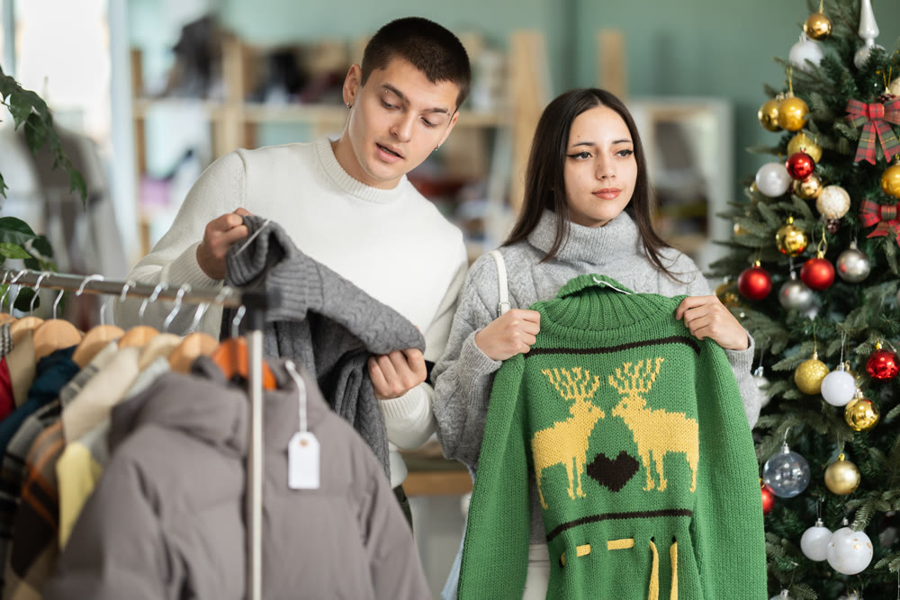 Couple chooses fashionable sweater in a clothing store during Christmas celebrations.