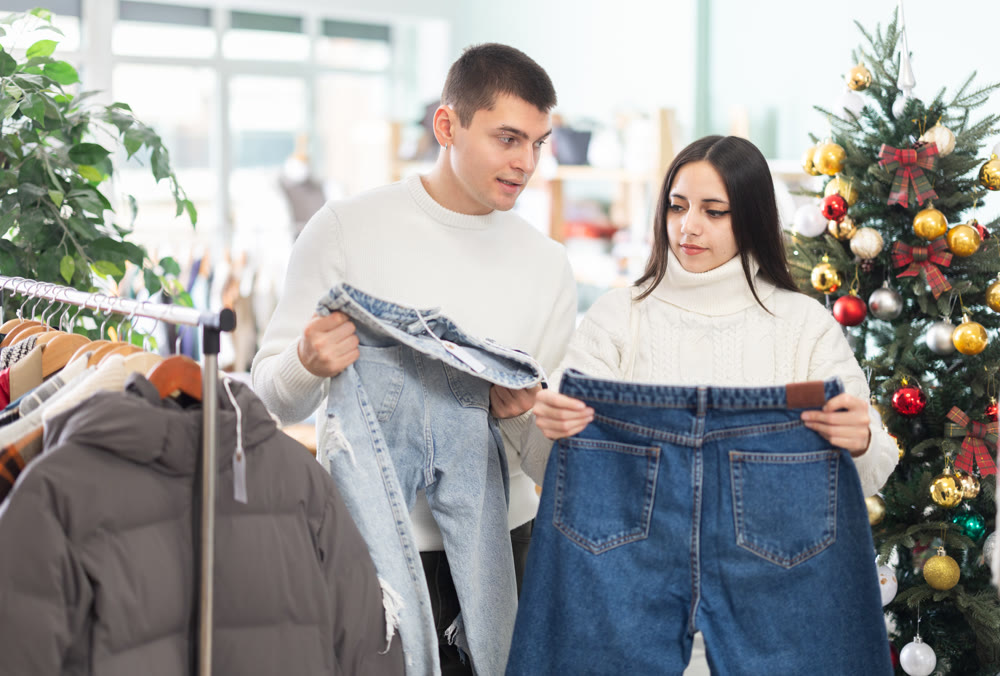 Young couple choosing jeans pantaloons in clothing store