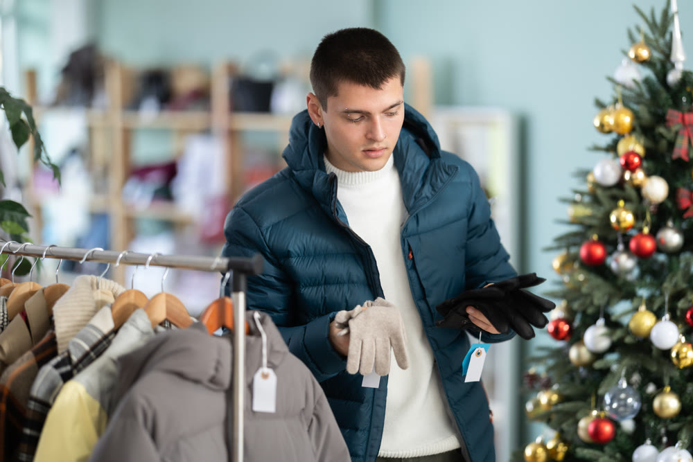 Young man choosing gloves in clothing store