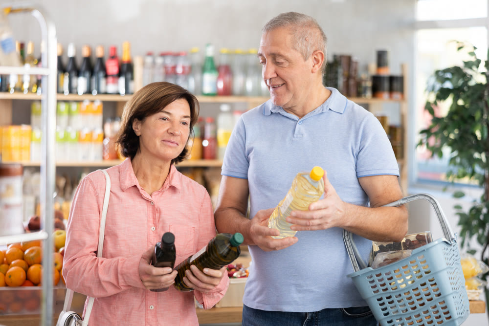 Mature couple buyer looks thoughtfully at bottles of vegetable oil