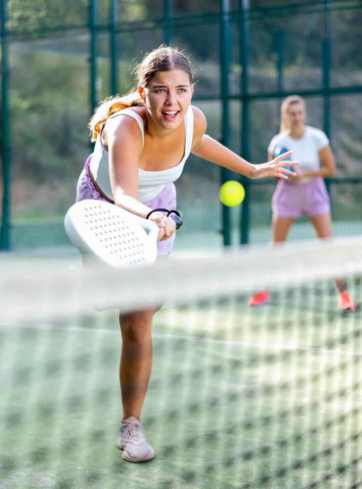 Active womans with enthusiasm playing padel on tennis court