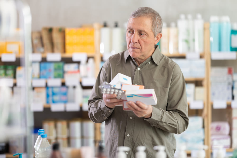 Elderly man with several packs of pills